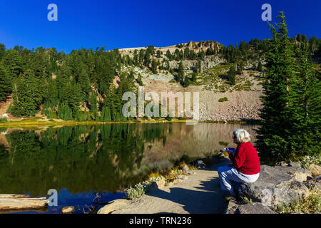 Frau sitzt bei Emerald Lake in den Lassen Volcanic National Park, Kalifornien Stockfoto