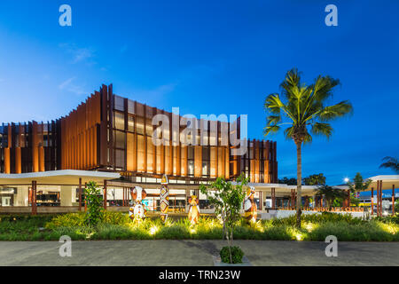 Die Fassade der Cairns Performing Arts Center in der Dämmerung beleuchtet. Eine Reihe von "bagu "heimischen Skulpturen sitzen an der Vorderseite des Zentrums. Cairn Stockfoto