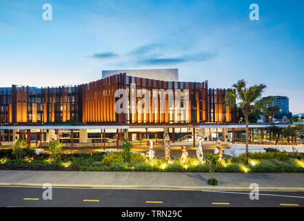 Die Fassade der Cairns Performing Arts Center in der Dämmerung beleuchtet. Eine Reihe von "bagu "heimischen Skulpturen sitzen an der Vorderseite des Zentrums. Cairn Stockfoto