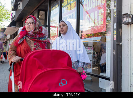 Zwei muslimische Frauen in hijabs, wahrscheinlich Schwestern, gehen Sie die 74th St. in Jackson Höhen treibt ein rotes Baby Stroller. Queens, NYC. Stockfoto