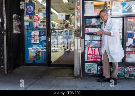 Ein älterer Mann seine Scratch Off Kontrolle Lottery ticket außerhalb einer kleinen Lebensmittelladen auf Roosevelt Ave. Unter der El in Jackson Heights, Queens, New York. Stockfoto