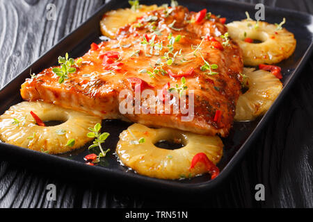 Lachs Gericht mit einem süßen und würzigen Sauce und saftige Ananas close-up auf einem Teller auf den Tisch. Horizontale Stockfoto