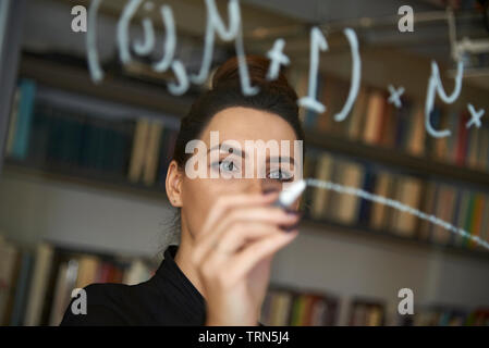 Weibliche computer Coder schreiben Sie ein komplexer Code auf ein Fenster in Ihrem Büro. Empowerment von Frauen und die Gleichstellung in der Arbeitswelt Stockfoto