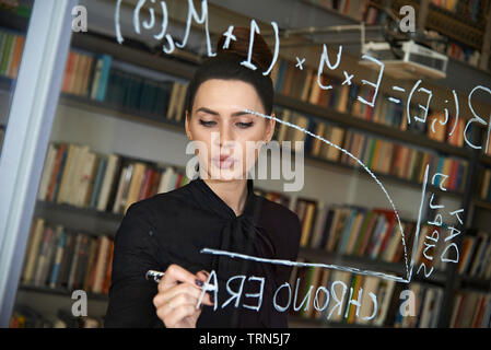 Weibliche computer Coder schreiben Sie ein komplexer Code auf ein Fenster in Ihrem Büro. Empowerment von Frauen und die Gleichstellung in der Arbeitswelt Stockfoto