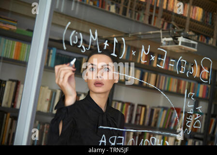 Weibliche computer Coder schreiben Sie ein komplexer Code auf ein Fenster in Ihrem Büro. Empowerment von Frauen und die Gleichstellung in der Arbeitswelt Stockfoto