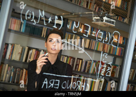 Weibliche computer Coder schreiben Sie ein komplexer Code auf ein Fenster in Ihrem Büro. Empowerment von Frauen und die Gleichstellung in der Arbeitswelt Stockfoto