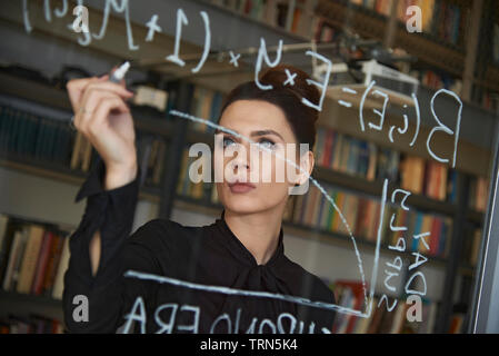 Weibliche computer Coder schreiben Sie ein komplexer Code auf ein Fenster in Ihrem Büro. Empowerment von Frauen und die Gleichstellung in der Arbeitswelt Stockfoto