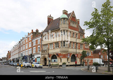 Wimbledon Village, ein wohlhabender Bereich von Südwesten London, UK. Zeigt kunstvoll verzierte ehemalige Bankgebäude und Geschäfte; Verbindungspunkt von High Street und Belvedere Road. Stockfoto