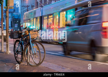 Nacht Zeit, Fahrräder geparkt und Straßenbahnen und Verkehr Pass in der Brunswick Street, Fitzroy, Victoria, Australien Stockfoto