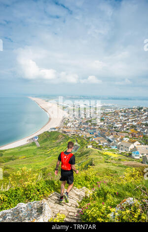 Jogger läuft steilen Weg von Portland Höhen auf der Isle of Portland in Richtung Chesil Beach und der viilage der Fortuneswell, Dorset, England, UK. Stockfoto