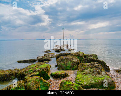 Eine Linie von Algen bedeckten Felsen führen, in der die Mündung auf der Lee auf Solent Strand. Stockfoto