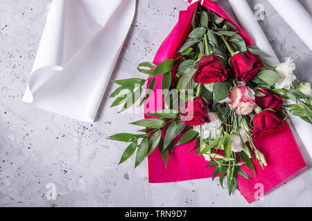 Schönen Blumenstrauß mit roten Rosen und grünen Blättern auf roten und weißen Papier - der Prozess des Erstellens einer Blumenstrauß Stockfoto