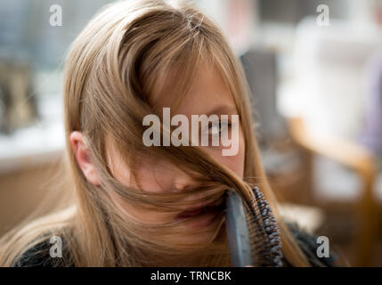 Hübsche, junge blonde Mädchen putzen ihr Haar und Suchen coy Stockfoto