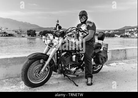 Mann in Skull t shirt und Schädel Maske auf einer Harley Davidson Motorrad am Meer, Kreta Griechenland Stockfoto