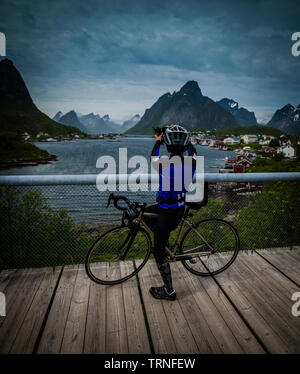 Eine weibliche Radfahrer hält ein Foto auf einem iphone, Norwegen, Sommer 2019. Stockfoto