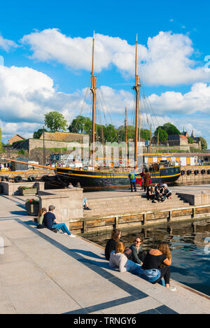 Oslo Hafen, Blick auf die jungen Menschen entspannend neben einem Kai im Hafen (Aker Brygge) in Oslo an einem Sommernachmittag, Norwegen.