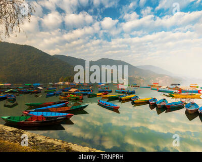 Nepal Boote mit verschiedenen Farben, der blaue Himmel Spiegelbild im Wasser. Phewa-see Pokhara Nepal. Stockfoto