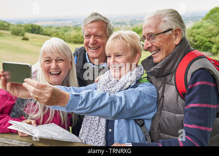 Gruppe von älteren Freunden Wandern in der Landschaft stehend durch Tor und unter Selfie auf Handy Stockfoto