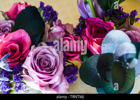 Eine Luftaufnahme einer Innen- Anordnung der Rosen mit schöner Duft, von Farbe in eine Vase für den Innen- Anzeige der verschönert mit Rosa und Lila Stockfoto