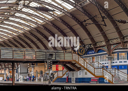 Der Bahnhof York mit seiner aufwendigen 19 Architektur und geschwungene Vordach. Geschäfte, Cafés und Passagiere sind auf den Plattformen. Stockfoto