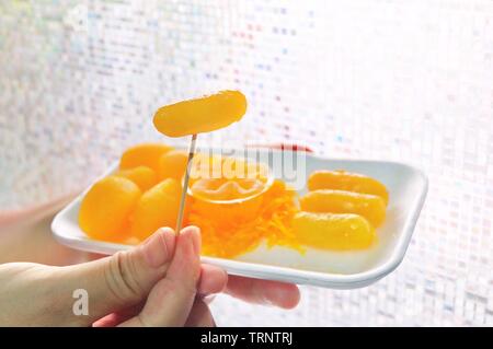 Traditionelle thailändische Dessert, Hand mit goldenen und süßen Eigelb oder Mung Bean Paste Teigtaschen mit Eigelb zubereitet in Sirup. Stockfoto