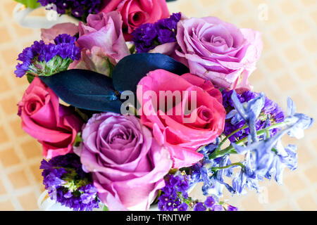 Eine Luftaufnahme einer Innen- Anordnung der Rosen mit schöner Duft, von Farbe in eine Vase für den Innen- Anzeige der verschönert mit Rosa und Lila Stockfoto