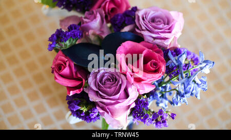 Eine Luftaufnahme einer Innen- Anordnung der Rosen mit schöner Duft, von Farbe in eine Vase für den Innen- Anzeige der verschönert mit Rosa und Lila Stockfoto