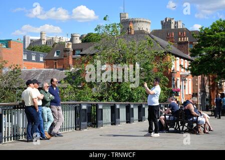 Eine Gruppe von Touristen fotografiert werden beim Stehen auf Windsor Bridge mit der Burg im Hintergrund, Berkshire England Großbritannien Stockfoto
