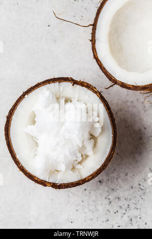 Kokosöl in einem coconut Shell auf grauem Hintergrund. Stockfoto