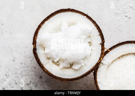 Kokosöl in einem coconut Shell auf grauem Hintergrund. Stockfoto