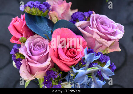Eine Luftaufnahme einer Innen- Anordnung der Rosen mit schöner Duft, von Farbe in eine Vase für den Innen- Anzeige der verschönert mit Rosa und Lila Stockfoto