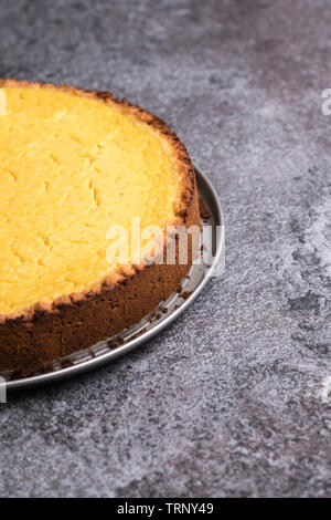 Leckere hausgemachte vegan Lemon cheesecake auf einer Platte, dunkelgrau Stein - Hochformat Raum auf der rechten Seite kopieren Stockfoto