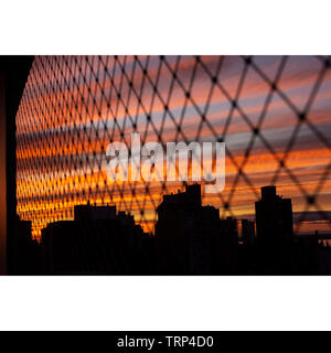 Dramatischer sonnenuntergang himmel von hinter dem Safety Net von einem Balkon Stockfoto