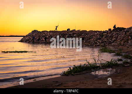 Junge fischen während eines goldenen Sonnenuntergang vom rivershore Stockfoto