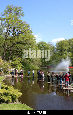 Besucher zum Keukenhof Gardens in der Nähe von Lisse in Südholland, Niederlande Kreuzung große Trittsteine durch eine Wasserfontäne in der zierteich. Stockfoto
