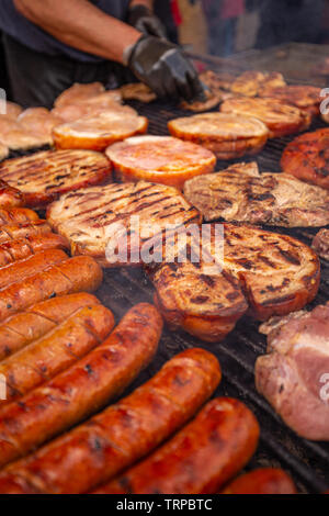 Verschiedene köstliche gegrillte Fleisch- und Wurstwaren über den Kohlen auf einem Grill Stockfoto