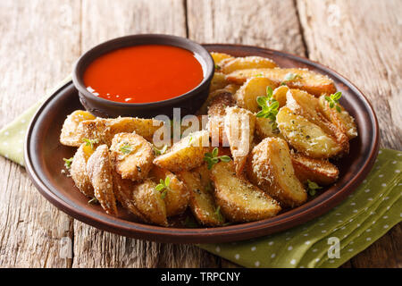 Leckerer snack von Potato Wedges mit Parmesan Käse und Kräutern mit Pfeffersauce close-up auf einem Teller auf den Tisch. Horizontale Stockfoto