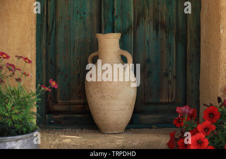 Eine traditionelle libanesische Terrakotta jar in einem Garten vor einem alten grünen Fenster. Stockfoto