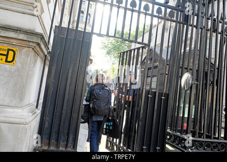 Eine Frau Fotograf durch Downing Street Tor Eingang von bewaffneten Polizisten erlaubt guard Stadt von Westminster, London England UK KATHY DEWITT Stockfoto