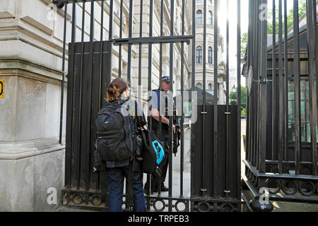 Eine Fotografin, die auf die Erlaubnis wartet, das Downing Street Gate in der City of Westminster, Central London England UK KATHY DEWITT zu passieren Stockfoto