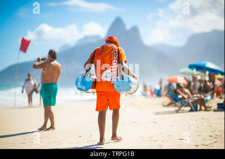 RIO DE JANEIRO - Februar, 2018: Eine junge brasilianische Hersteller verkaufen kalter Mate, die Südamerikanische Tee, Spaziergänge Vergangenheit Touristen entspannen am Strand von Ipanema. Stockfoto