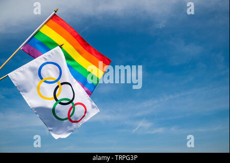 LONDON - Mai 4, 2019: Eine olympische Flagge hängt zusammen mit der Gay Pride Regenbogen Flagge unter hellen sonnigen blauen Himmel. Stockfoto