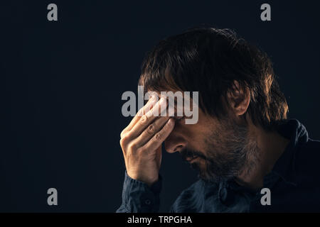 Traurig Mitte erwachsenen Mann deprimiert. Low Key Portrait von männliche Person Gefühl untröstlich. Die verzweifelten Zustand des Geistes und der geistigen Gesundheit Konzept. Stockfoto