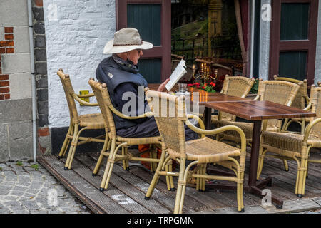 Mann außerhalb ein Cafe mit einem Buch sitzen. Stockfoto