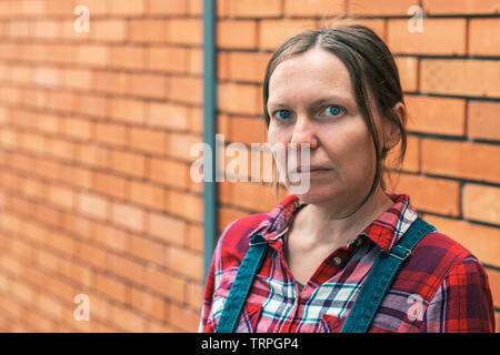 Weibliche Landwirt denken. Outdoor Portrait von Erwachsenen kaukasischen stehende Frau vor dem Bauernhaus. Stockfoto