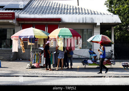 CAINTA, Rizal, Philippinen - Juni 9, 2019: Fußgänger vorbei eine behelfsmäßige Store einen Bürgersteig entlang an einem heißen, sonnigen Tag. Stockfoto
