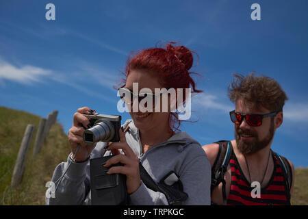 Junge kaukasier Frau nehmen, einige Bilder mit einer kleinen Tasche Kamera mit Ihrem Partner auf der Suche. Sie sind komfortabel und gemeinsam Spaß haben Stockfoto