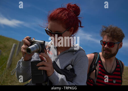 Junge kaukasier Frau nehmen, einige Bilder mit einer kleinen Tasche Kamera mit Ihrem Partner auf der Suche. Sie sind komfortabel und gemeinsam Spaß haben Stockfoto