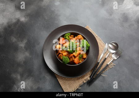 Traditionelle hausgemachte Ungarische Rindfleisch Eintopf, Gulasch mit Kartoffeln, Karotten, Tomaten, Brokkoli in eine Schüssel geben. Stockfoto