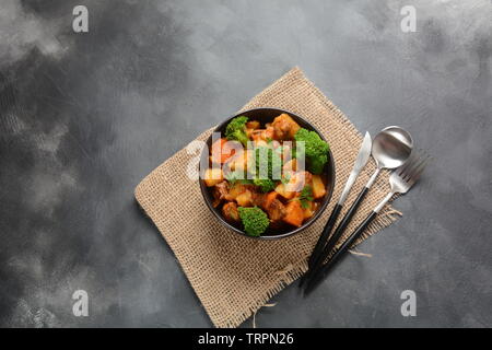 Traditionelle hausgemachte Ungarische Rindfleisch Eintopf, Gulasch mit Kartoffeln, Karotten, Tomaten, Brokkoli in eine Schüssel geben. Stockfoto